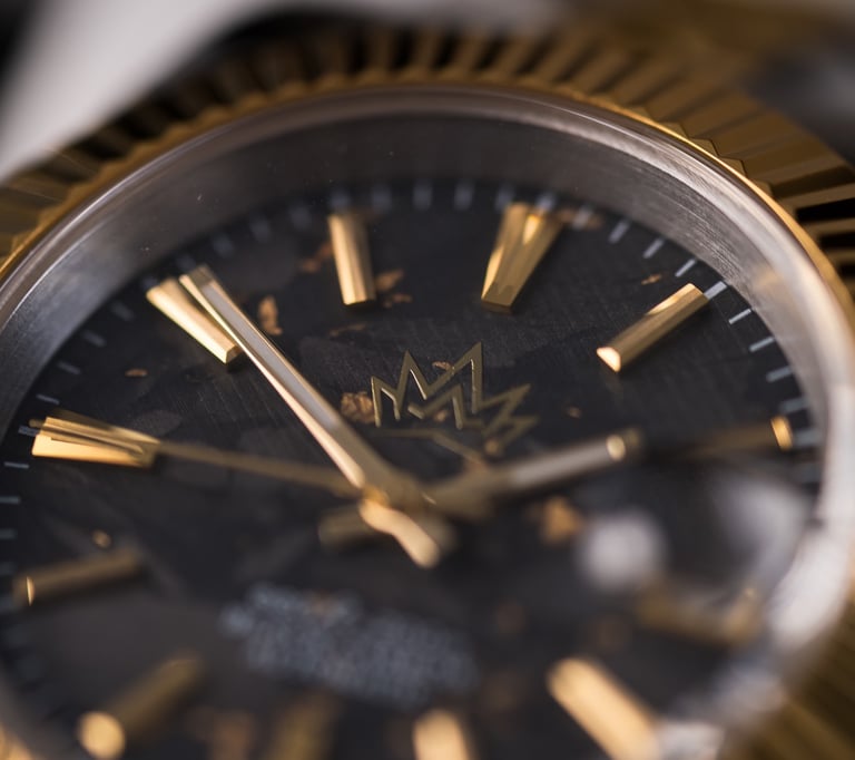 Macro view of a luxury gold watch with a black textured dial and gold fluted bezel.