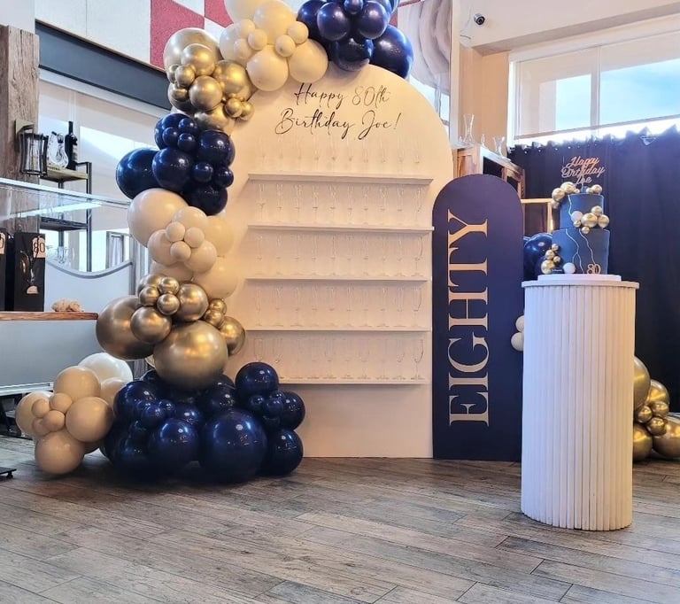 Balloon garland paired with our champagne/treat wall for an 80th birthday