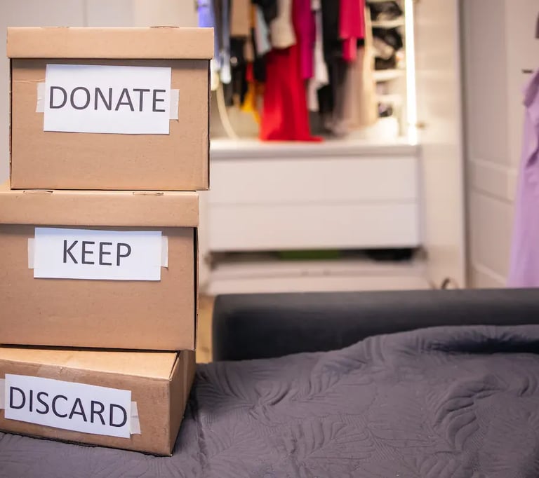 Cardboard boxes labeled donate, keep, and discard for closet organization and decluttering clothes.