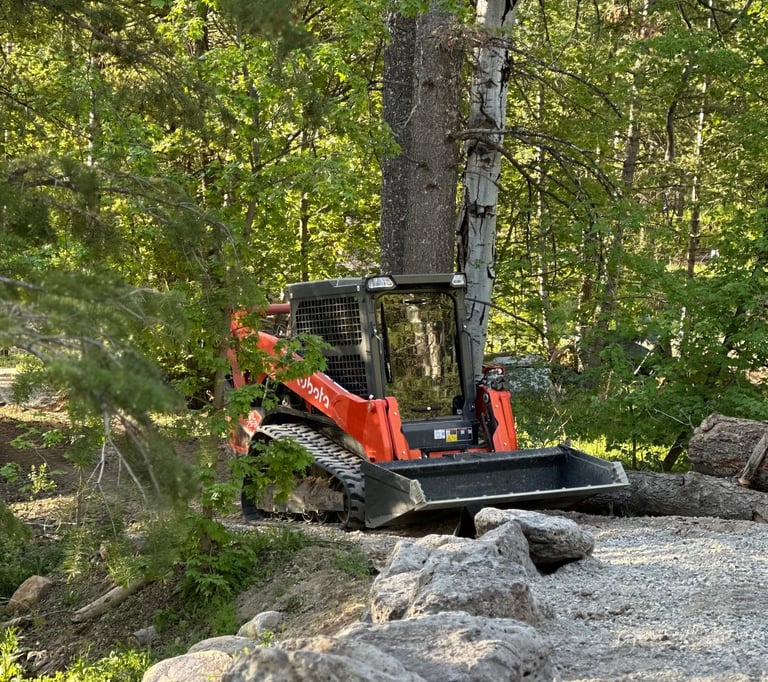 Kubota skid steer working on a boulder wall and grade work in northern utah