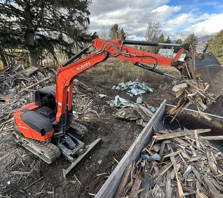 Kubota excavator loading demo debris into a dump trailer