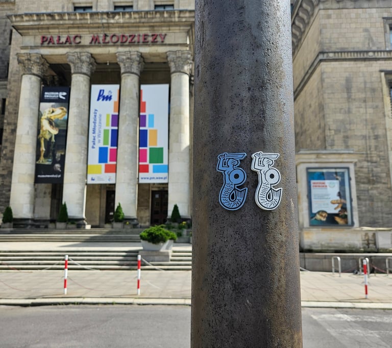 Zdjęcie dwóch magnesów z Syrenkami Warszawskimi na tle Pałacu młodzieży.