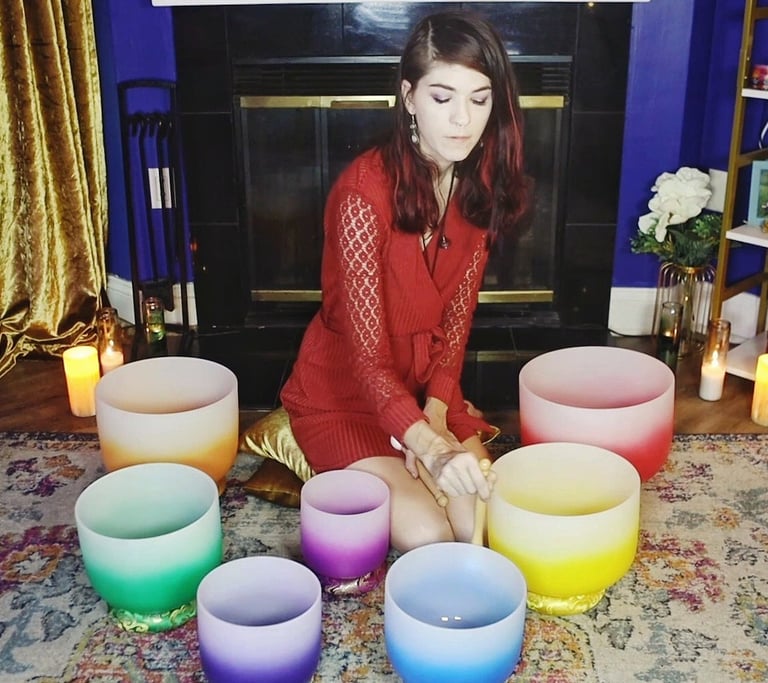 a woman sitting on a rug with crystal singing bowls and candles