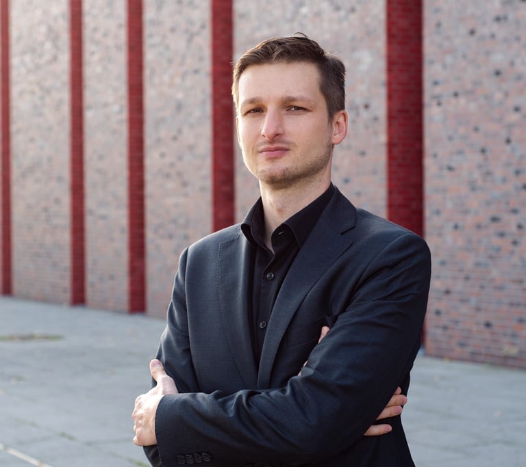 a man in a suit and tie standing in front of a brick wall