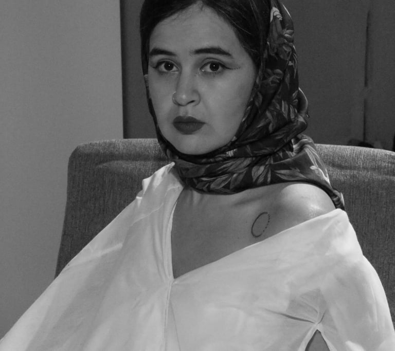 Black and white portrait of a woman wearing a floral headscarf and off-the-shoulder white blouse.