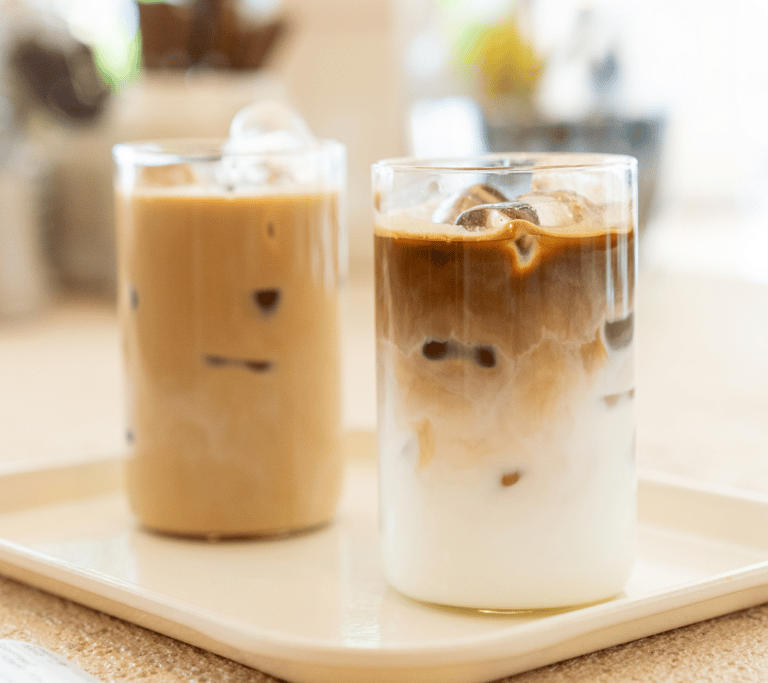 Two iced coffees on a single tray at a sunshine-soaked cafe.
