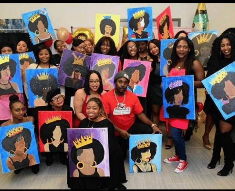 A group of people posing with their finished afro queen paintings at a paint and sip event.