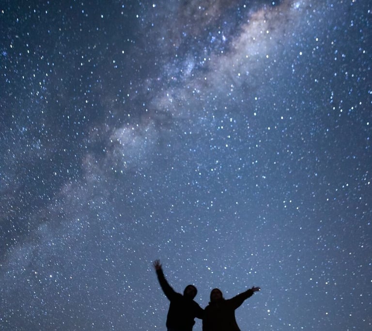 two people standing on a hill with their arms up
