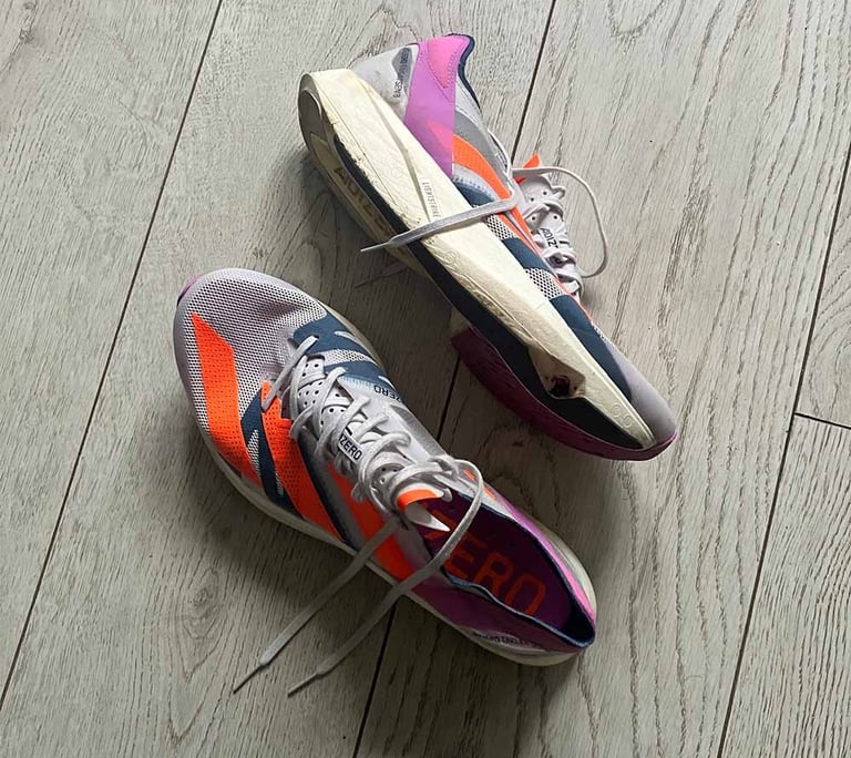 a pair of white adidas running shoes with pink and orange stripes