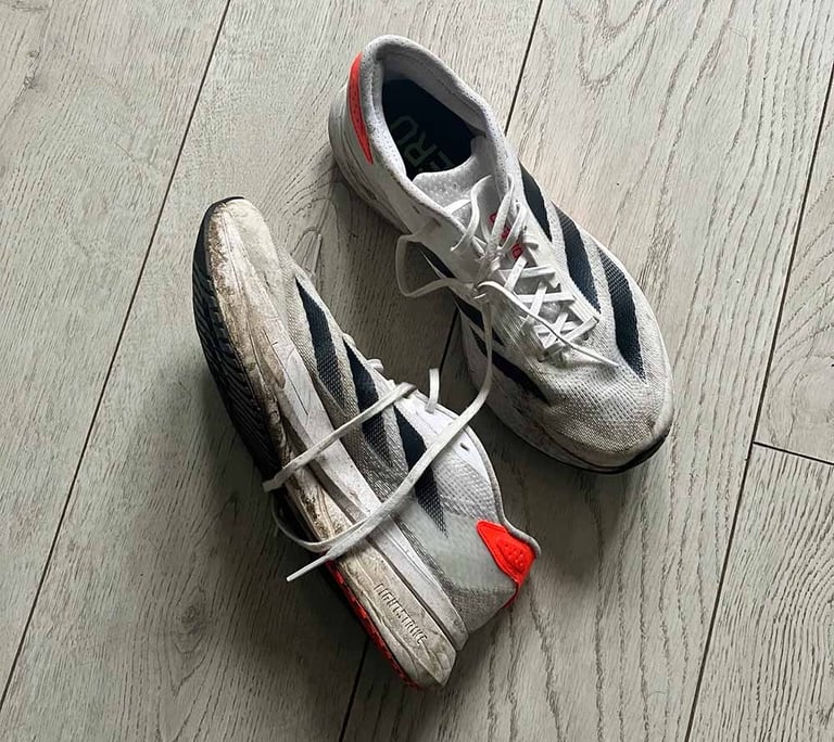 a pair of white adidas running shoes with black stripes