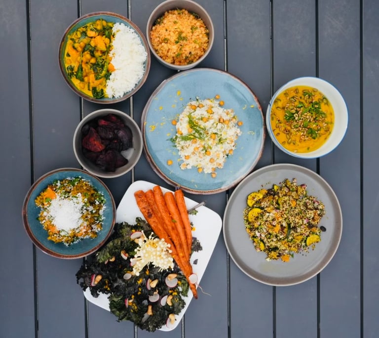 a table with bowls of vegetarian plant-based food and a bowl of vegetables carrots chickpeas