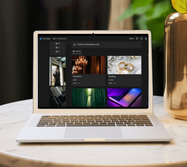 Silver laptop on a marble table displaying a dark mode personal finance savings tracker dashboard.