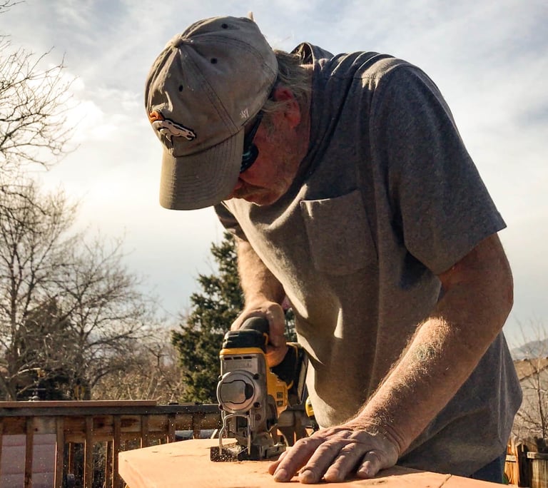 Brewer Construction carpenter using an impact driver on a wooden deck structure in Evergreen.