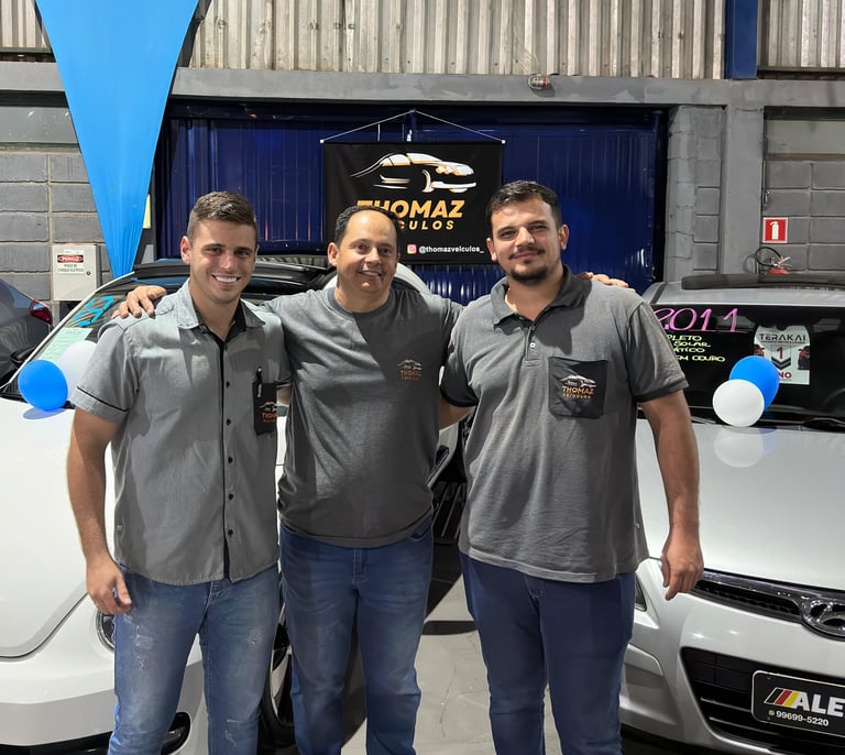 two men standing next to each other in front of a car