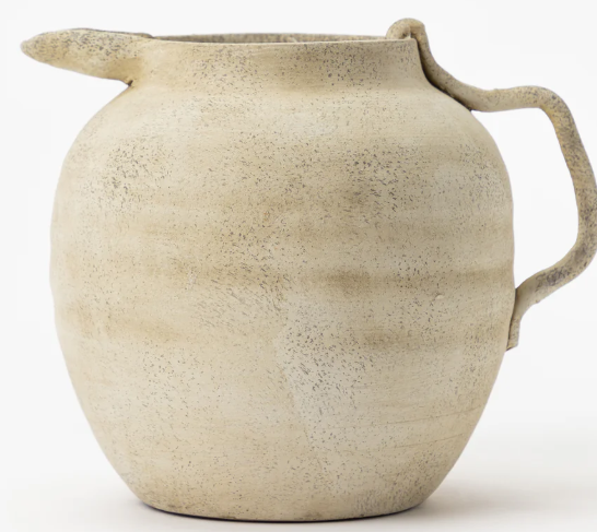Rustic handmade beige ceramic pitcher with a textured matte finish and organic handle.