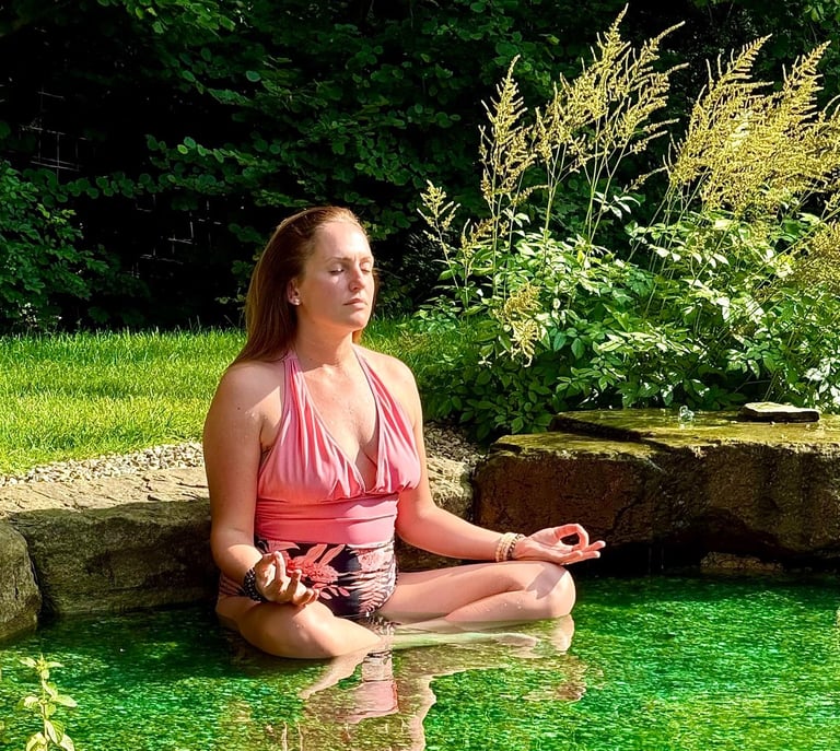 A picture of Alena Booth meditating in a natural lake in UK