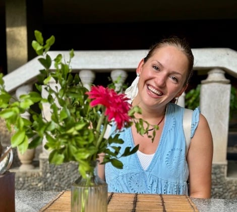 an image of Alena Booth smiling next to Red flowers in India