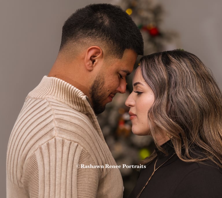 a man and woman standing next to a christmas tree