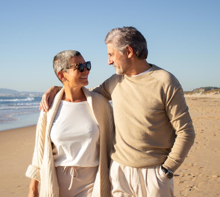 Happy retired expat couple on Murcia beach enjoying Spanish lifestyle with insurance protection