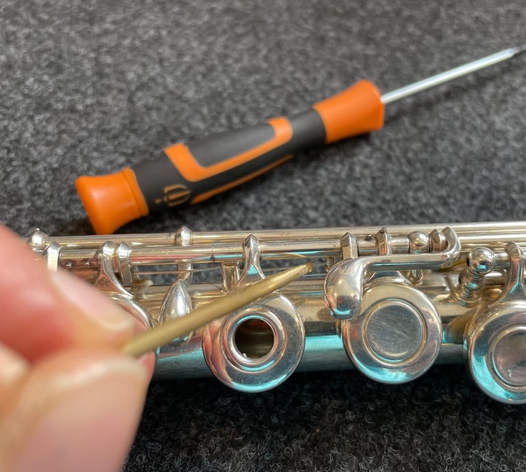 gros plan sur une main tenant un outils pour entretenir une flûte traversière