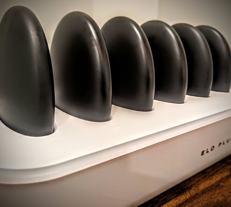 Elo Plus hot stone massage set with black basalt stones in a white warming station charger.