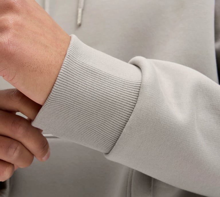 Close-up of a light gray hoodie sleeve showing the ribbed knit cuff and soft fleece cotton fabric.