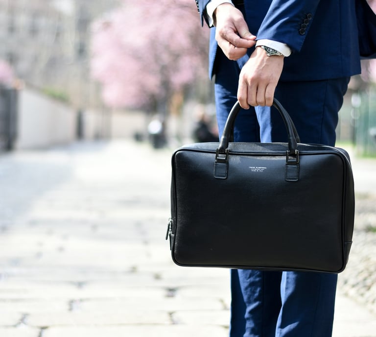 imagen de hombre de traje azul sosteniendo un maletín tapándose un reloj