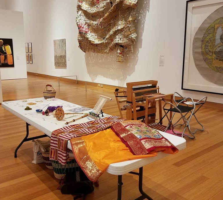 Photo from inside the Harn Museum of Art with a display of weavings and weaving tools.