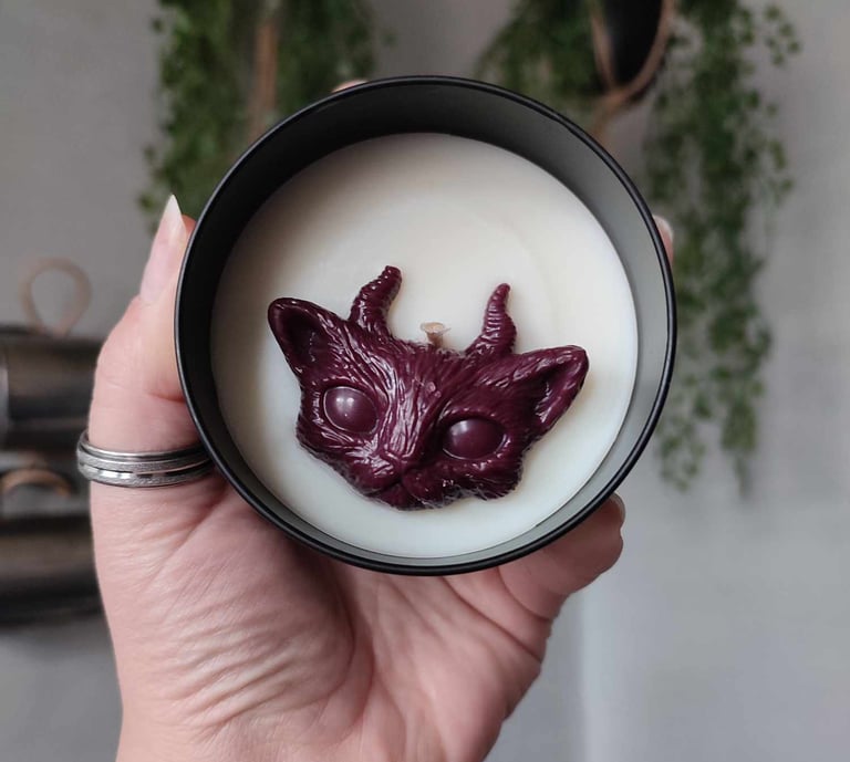 Bougies à la cire blanche, avec un fondant en forme de chat cornu, bordeaux. Contenant en métal noir