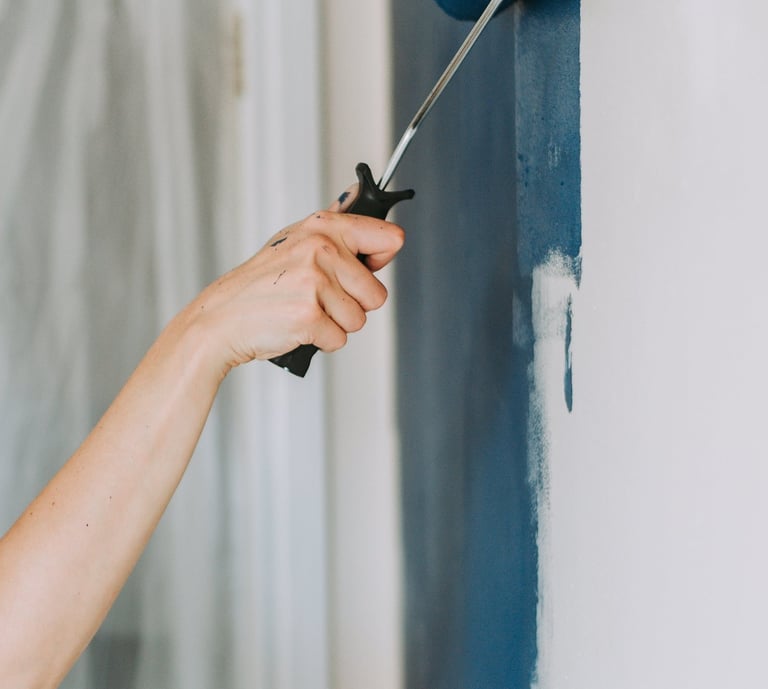 a woman is painting a wall with a blue paint roller