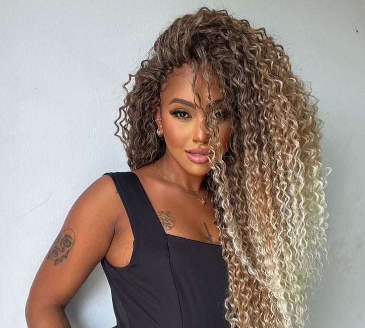 a woman with long curly hair (tree braids) and a black dress