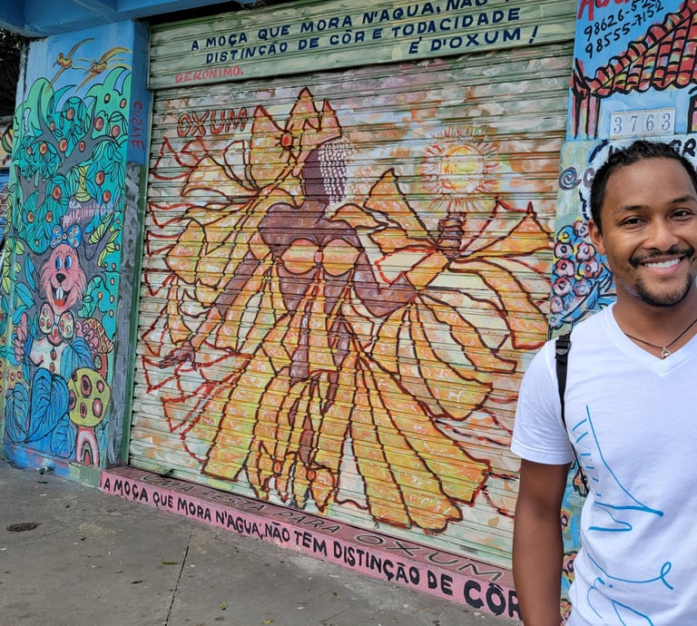 Wil smiling with a coconut in hand in Salvador in front of a drawing of Oshun