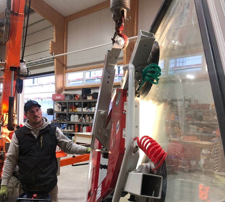 Schreinermeister Ferdinand Volk mit Glasscheibe am roten Vakuum-Saugheber in der Halle.