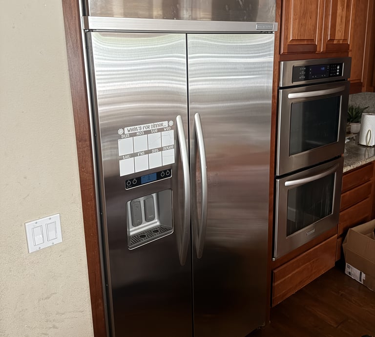 Built-in stainless steel French door refrigerator next to double wall ovens.