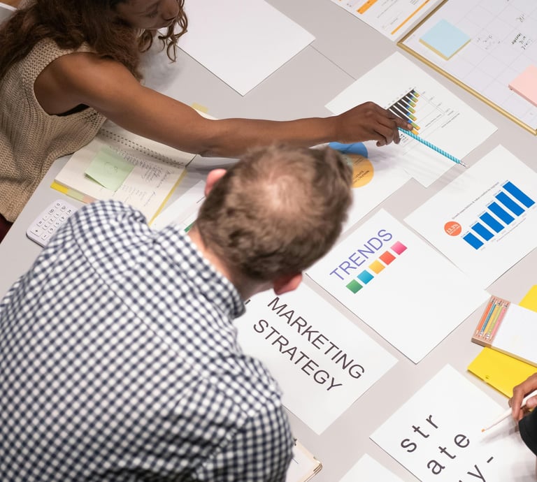 A marketing team reviews business growth charts and strategy documents during a planning session.