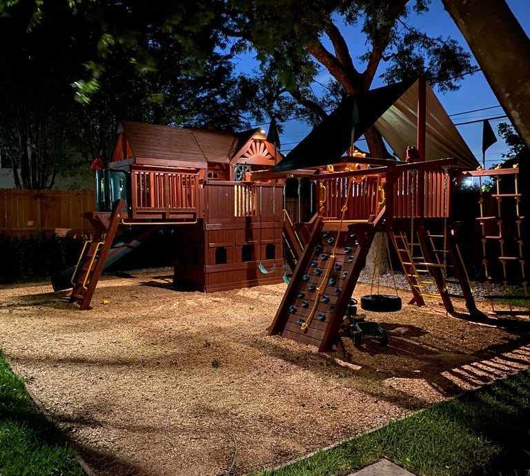 a playground area with a wooden playground that has lights on it structure