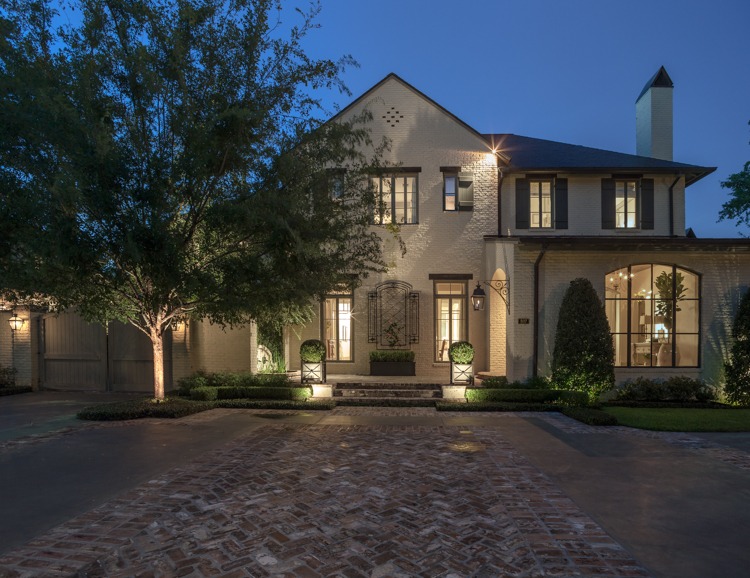 a large house with brickwork and a brick wall and lighting planters at front steps