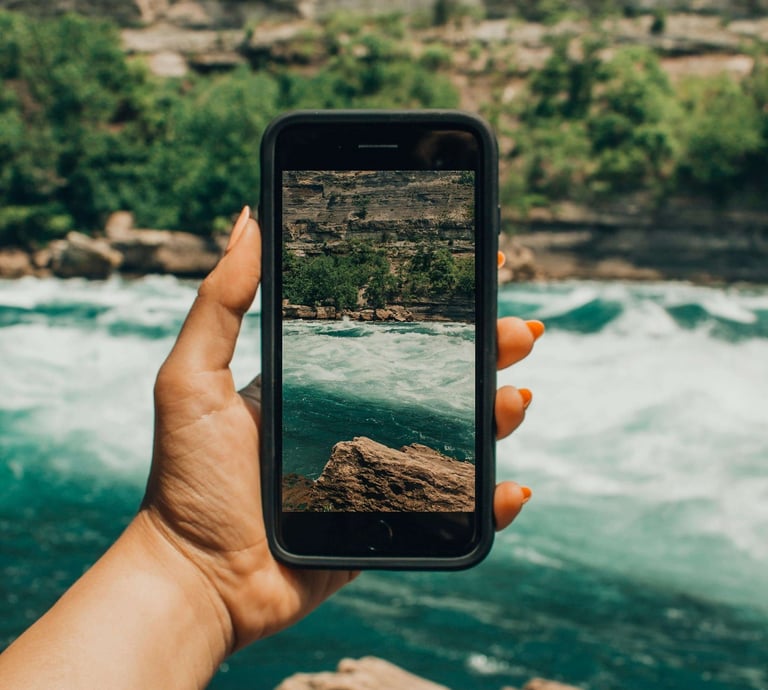 Persona sosteniendo un iPhone Km0 frente a un río, simbolizando la conexión entre tecnología y naturaleza.