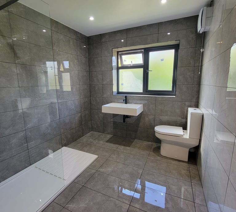 Completed family bathroom in Birmingham with modern tiles and wall mounted sink 
