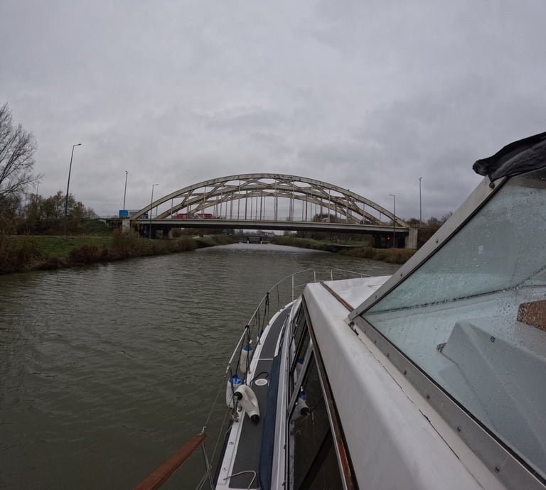 a boat traveling down a river with a bridge in the background