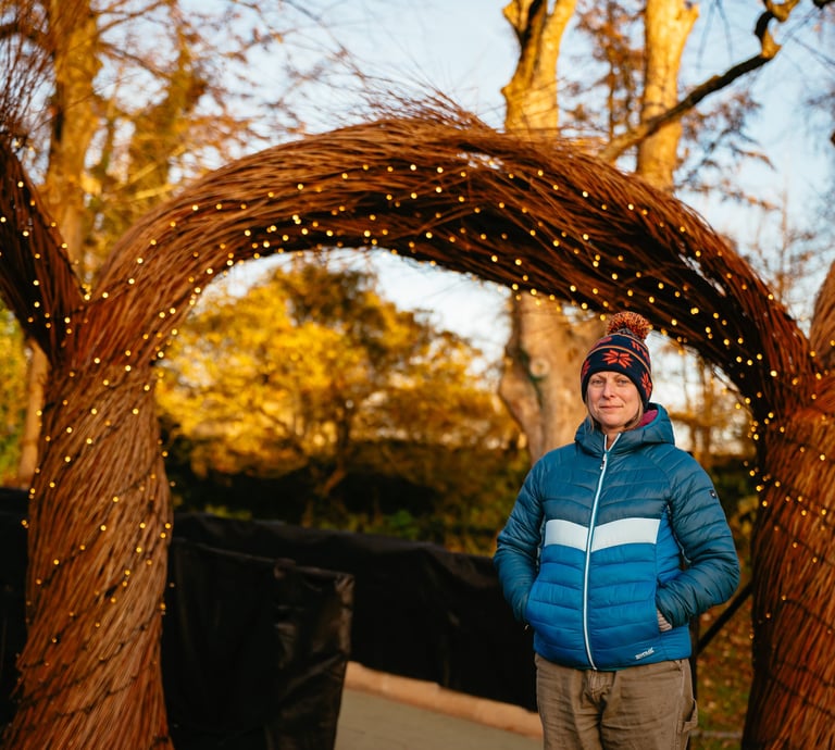 Hannah standing in front of 3m high Willow Arch for Christmas at Bute Park