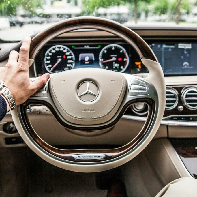 A person holding a steering wheel while driving, representing our professional car service.