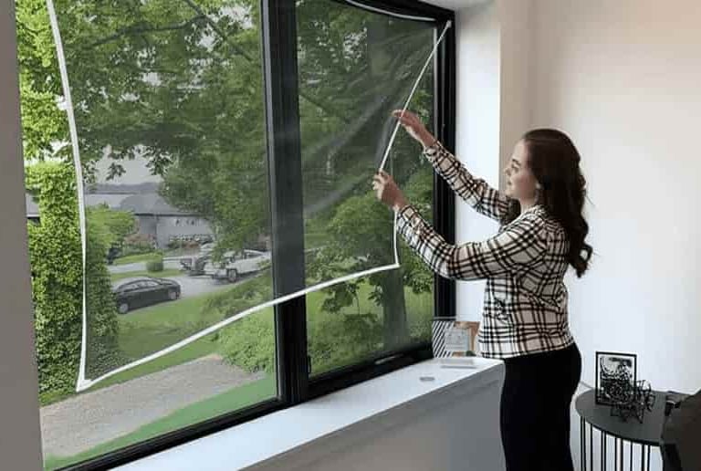 A technician carefully installing a mosquito net on a window in a cozy Sarjapur home.