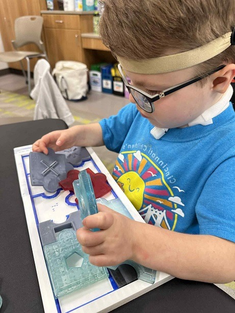 young visually impaired child focusing on a tactile puzzle