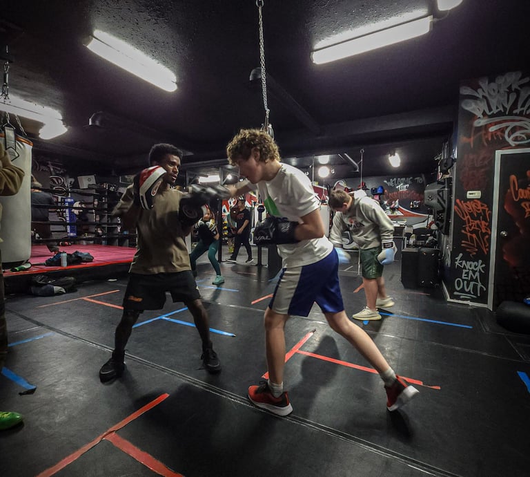 two men training with boxing gloves and pads