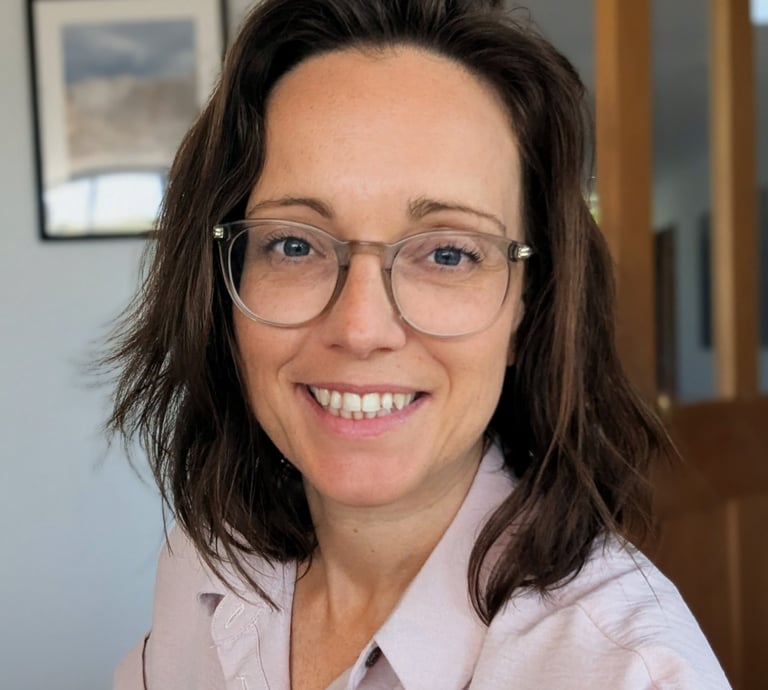 A professional female tutor with brown hair and clear-framed glasses smiling.