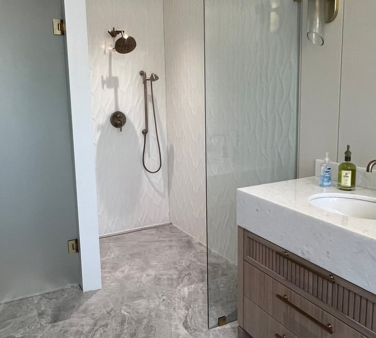 Modern master bathroom featuring a walk-in shower with textured tile and marble vanity.
