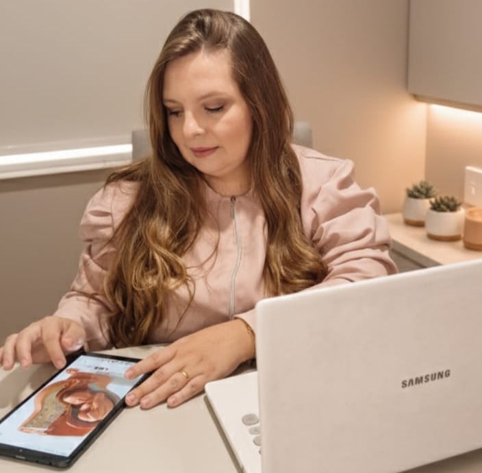 Fisioterapeuta analisando um tablet que mostra um útero com bebê.