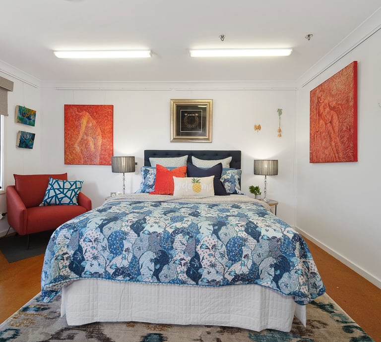 Cozy bedroom at Marche Home Stay with a queen bed, colourful artwork, soft lighting, and a welcoming, homely atmosphere.