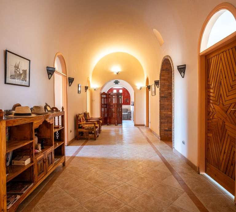Elegant nubian style villa hallway with arched ceilings, tiled floors, and rustic wooden furniture.